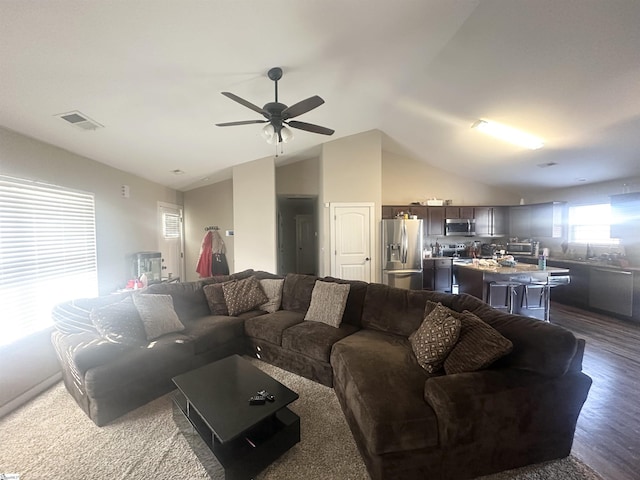 living area featuring vaulted ceiling, visible vents, dark wood-style flooring, and ceiling fan