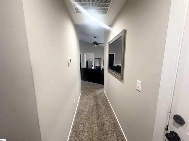 hallway featuring visible vents, carpet flooring, baseboards, and vaulted ceiling