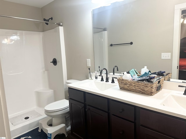 full bath with a sink, a shower, toilet, and double vanity