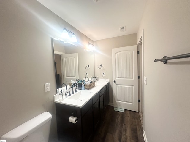 full bathroom featuring visible vents, toilet, wood finished floors, and a sink