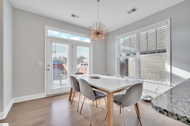 dining space featuring visible vents, an inviting chandelier, baseboards, and wood finished floors