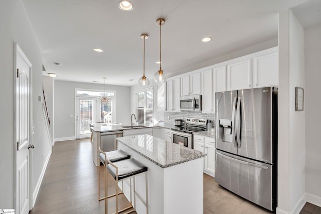 kitchen with a center island, decorative backsplash, appliances with stainless steel finishes, a peninsula, and a sink