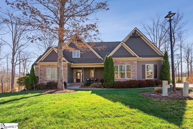 craftsman house featuring stone siding and a front lawn