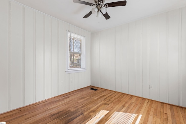 spare room featuring visible vents, a ceiling fan, and hardwood / wood-style floors