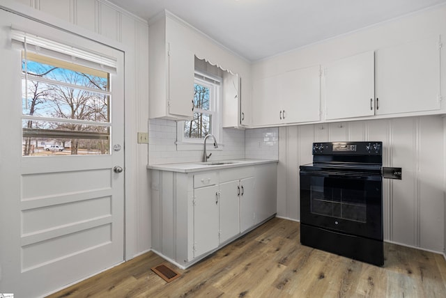 kitchen featuring white cabinetry, light countertops, black range with electric cooktop, and a sink