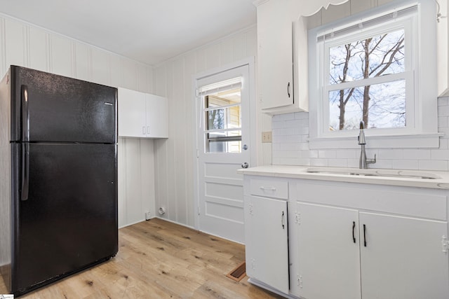 kitchen with decorative backsplash, a healthy amount of sunlight, freestanding refrigerator, and a sink