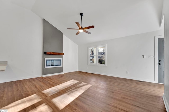 unfurnished living room featuring baseboards, wood finished floors, a glass covered fireplace, and a ceiling fan