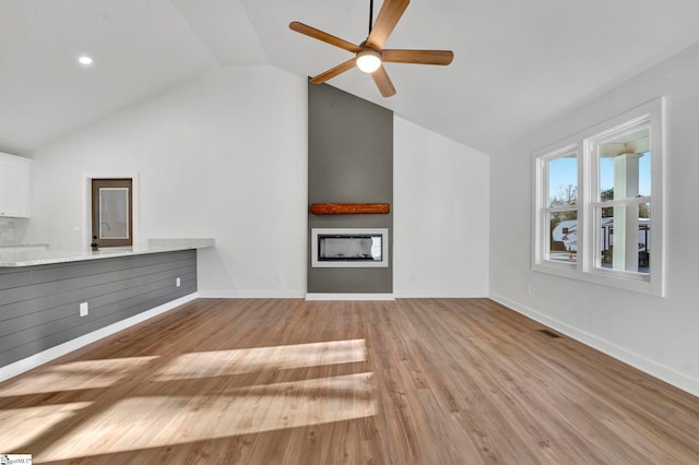 unfurnished living room with a ceiling fan, wood finished floors, baseboards, visible vents, and a fireplace