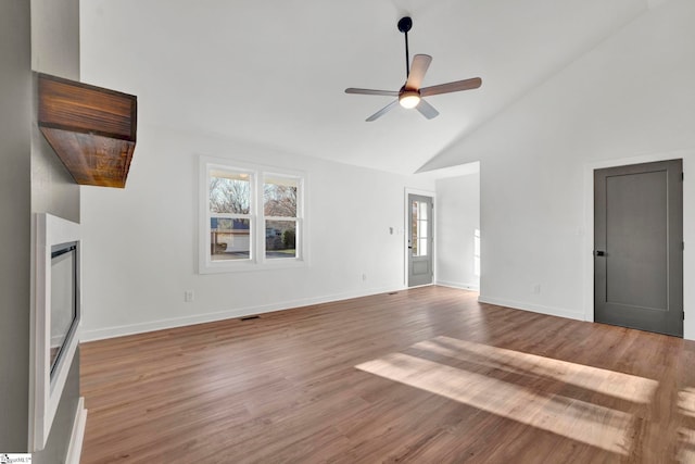 unfurnished living room with a ceiling fan, wood finished floors, baseboards, and high vaulted ceiling