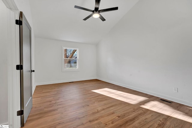 spare room featuring baseboards, light wood-type flooring, ceiling fan, and vaulted ceiling