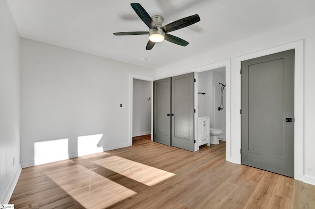 unfurnished bedroom featuring light wood-style floors, baseboards, ensuite bathroom, and ceiling fan