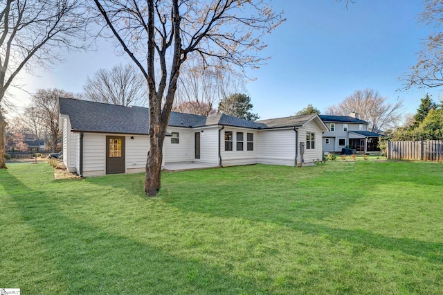 back of house featuring a lawn, a chimney, a patio, and fence