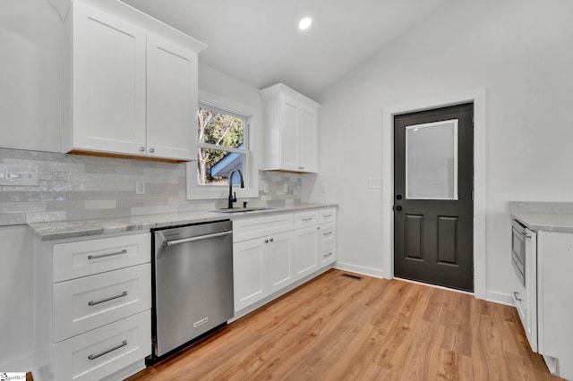 kitchen featuring visible vents, a sink, light wood finished floors, dishwasher, and vaulted ceiling