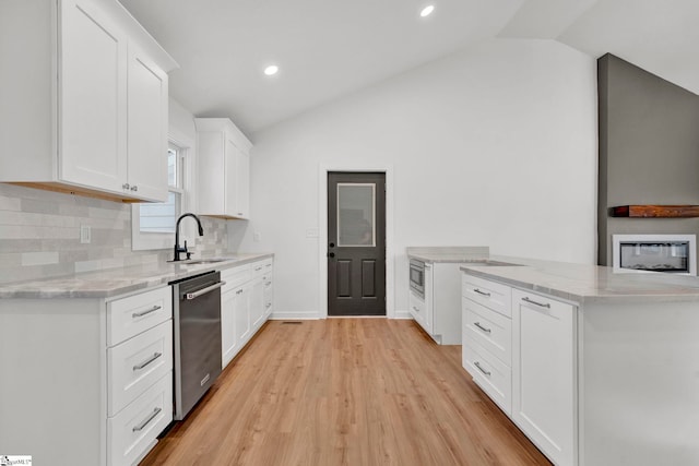 kitchen featuring light stone counters, a sink, vaulted ceiling, appliances with stainless steel finishes, and tasteful backsplash