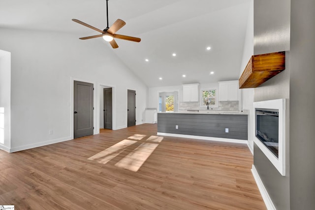 kitchen with white cabinetry, light countertops, open floor plan, and light wood-type flooring