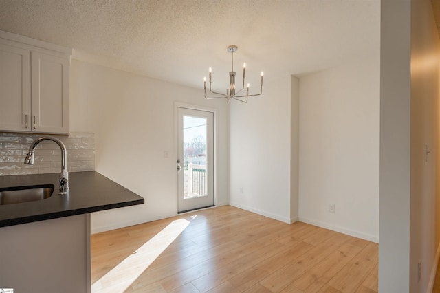 dining space featuring a textured ceiling, light wood-style floors, baseboards, and a chandelier