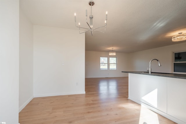 kitchen featuring a chandelier, dark countertops, light wood-style floors, and decorative light fixtures