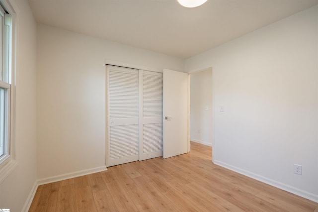 unfurnished bedroom with light wood finished floors, baseboards, and a closet