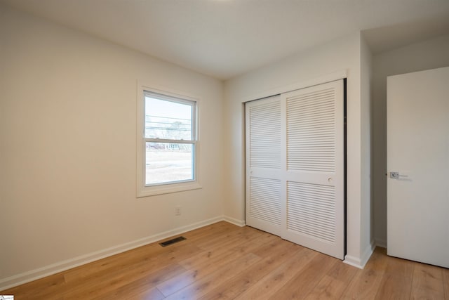 unfurnished bedroom with visible vents, baseboards, light wood-style floors, and a closet