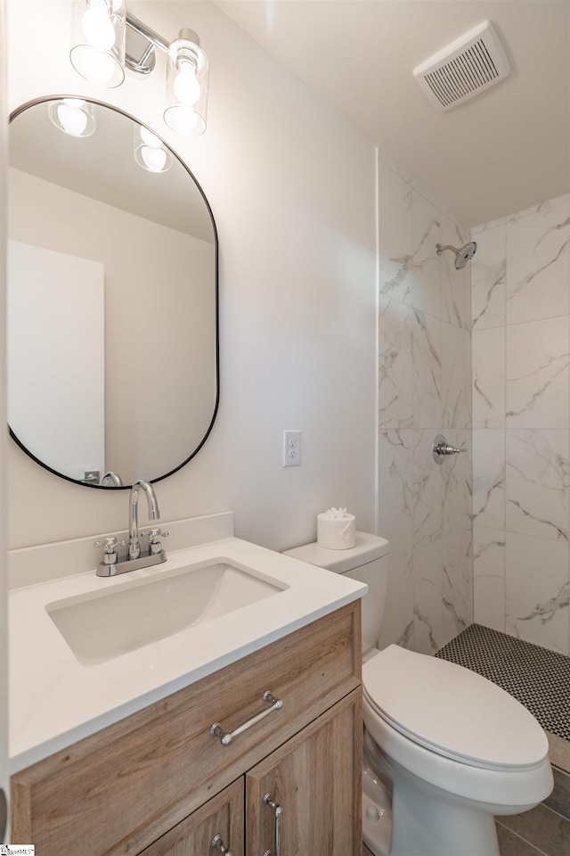 bathroom with vanity, toilet, visible vents, and a marble finish shower