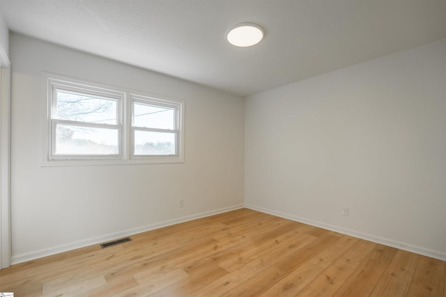 spare room featuring light wood-type flooring, baseboards, and visible vents