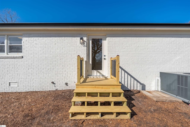 doorway to property with crawl space, brick siding, and central AC