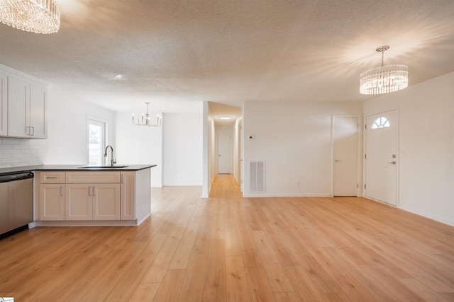 kitchen featuring visible vents, light wood-type flooring, a sink, dishwasher, and a chandelier