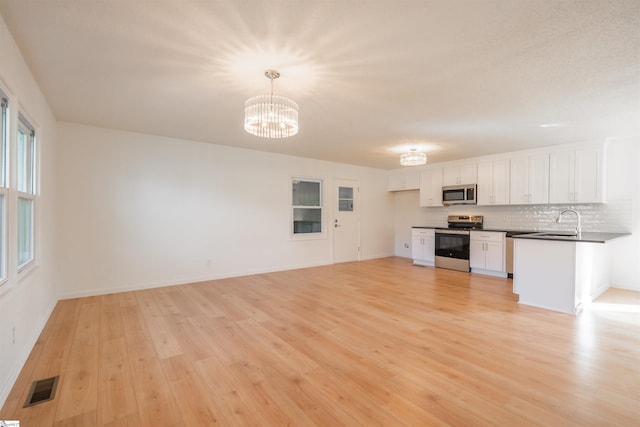 kitchen with visible vents, a sink, dark countertops, stainless steel appliances, and light wood finished floors