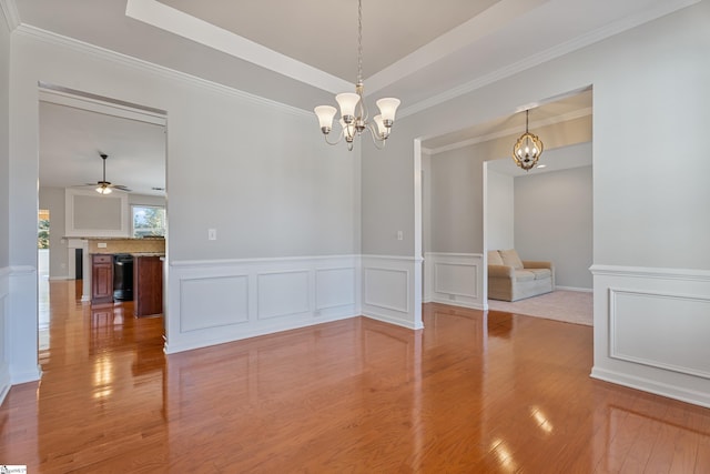 spare room with a raised ceiling, a decorative wall, and wood finished floors