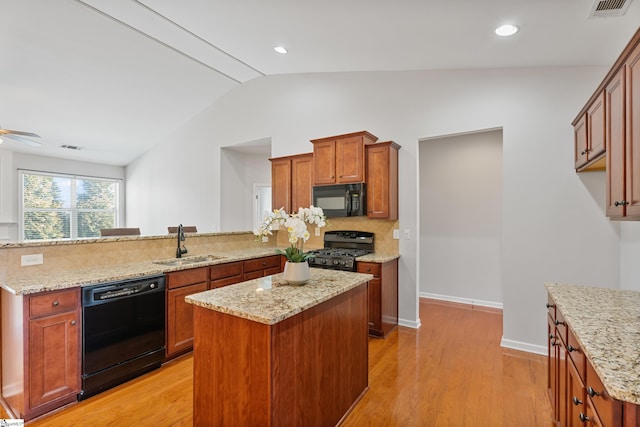 kitchen featuring light wood-style flooring, a peninsula, black appliances, and a sink