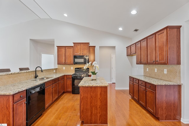 kitchen with a sink, visible vents, black appliances, and light wood finished floors