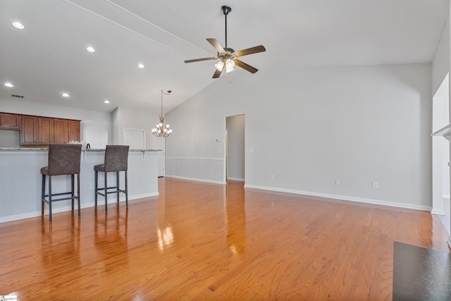 unfurnished living room featuring light wood-style flooring, recessed lighting, ceiling fan with notable chandelier, and baseboards