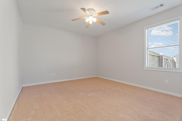 spare room with visible vents, light carpet, baseboards, and a ceiling fan