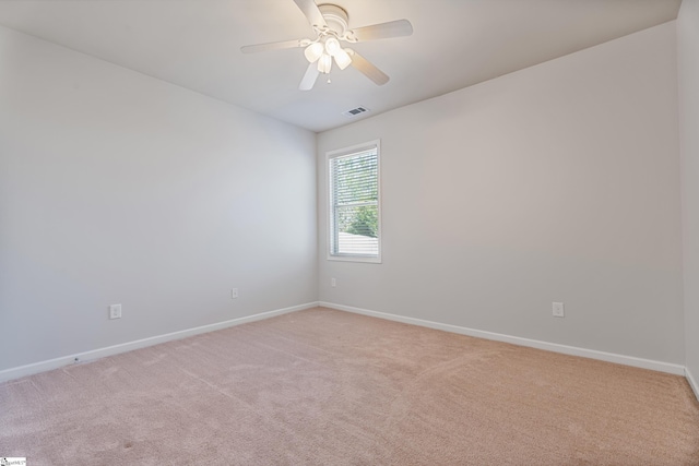 empty room with light carpet, visible vents, a ceiling fan, and baseboards