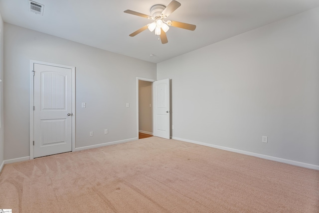 unfurnished bedroom with light carpet, visible vents, a ceiling fan, and baseboards