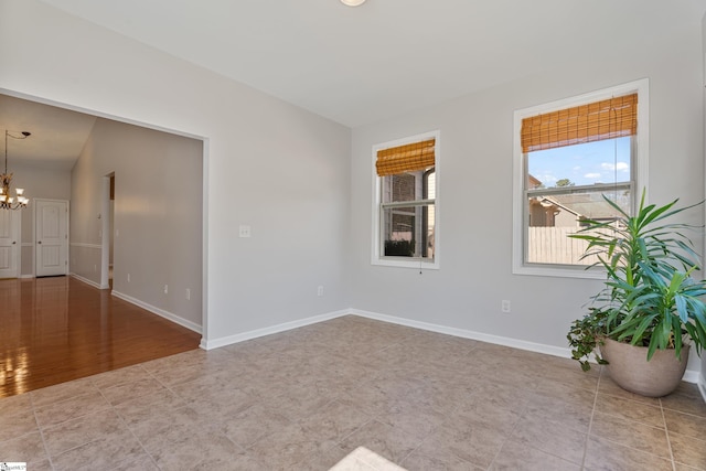 empty room with baseboards and a chandelier