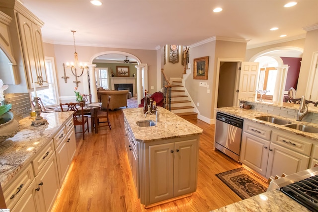 kitchen with light wood finished floors, a fireplace, arched walkways, a sink, and dishwasher