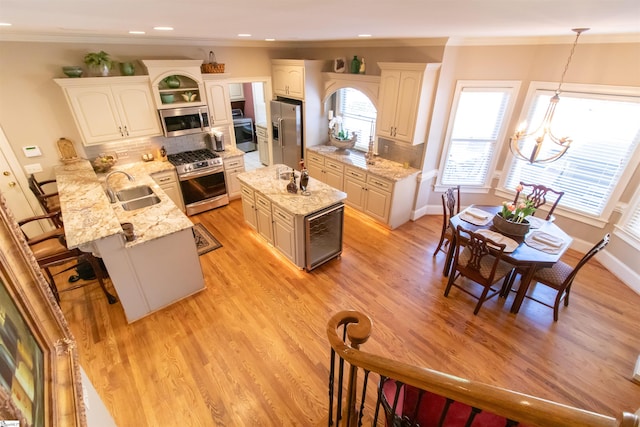 kitchen with light wood finished floors, a peninsula, stainless steel appliances, and a sink