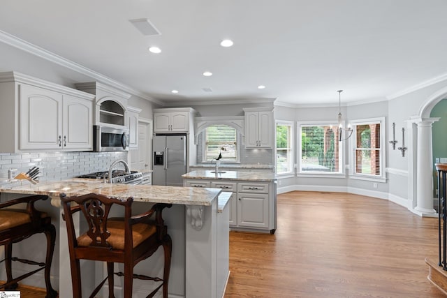 kitchen with a breakfast bar, stainless steel appliances, light wood-style floors, a peninsula, and crown molding