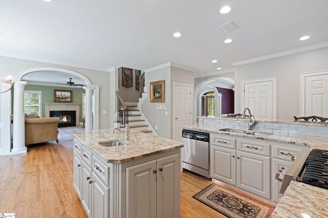 kitchen with arched walkways, a glass covered fireplace, dishwasher, and a sink