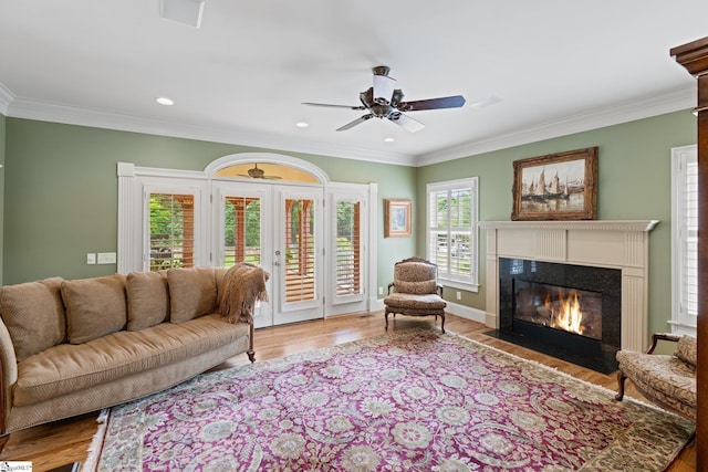 living area with a fireplace with flush hearth, wood finished floors, recessed lighting, and ornamental molding