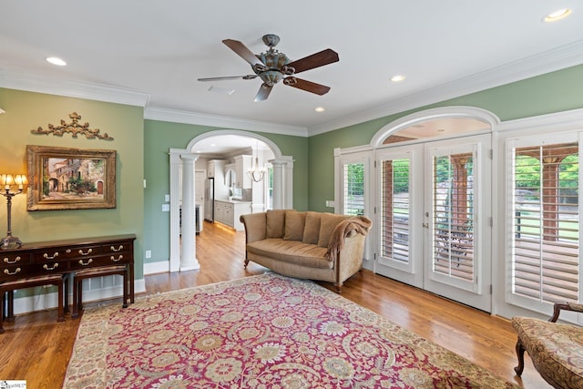 living area with a wealth of natural light, arched walkways, wood finished floors, and ornamental molding