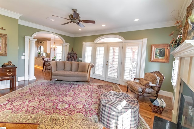 living area with arched walkways, wood finished floors, ornamental molding, and ornate columns