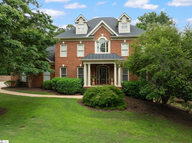 view of front of home with brick siding, a front lawn, and roof with shingles