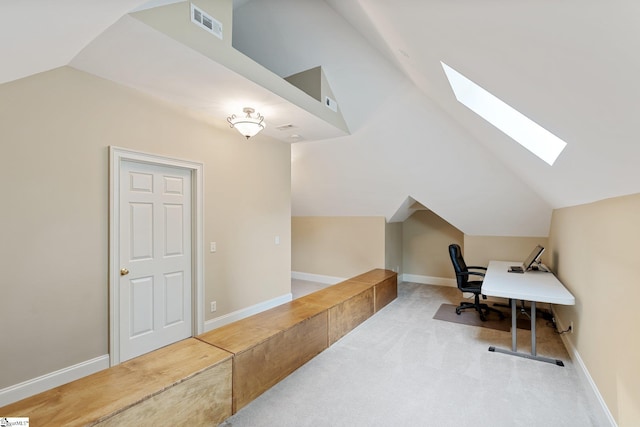 carpeted office space featuring vaulted ceiling with skylight, baseboards, and visible vents