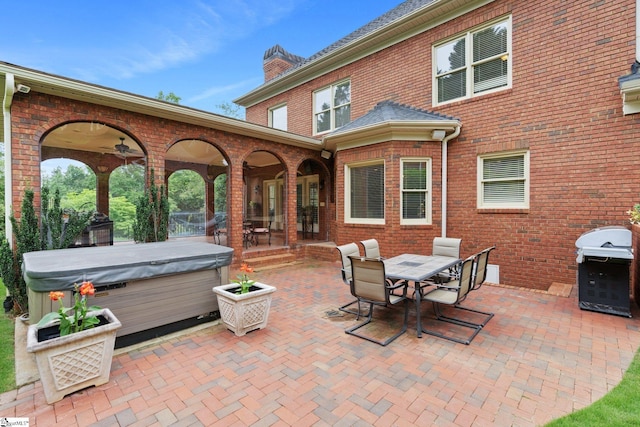 view of patio / terrace with outdoor dining space, ceiling fan, grilling area, and a hot tub