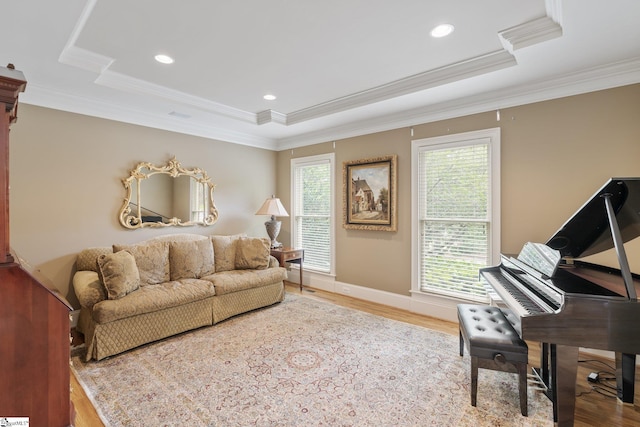 living area with ornamental molding, a tray ceiling, and wood finished floors