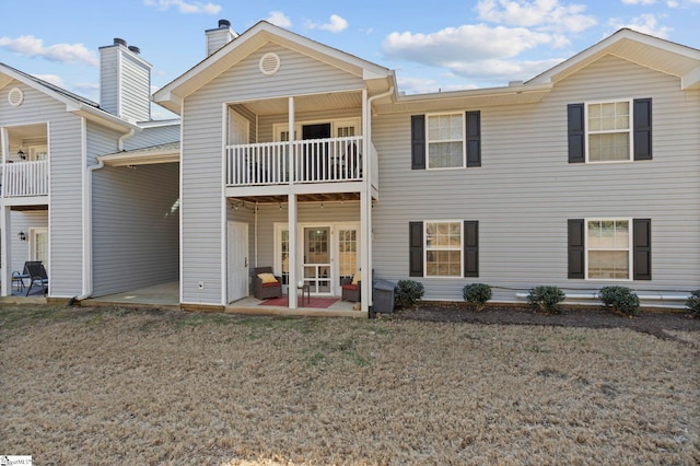 rear view of property with a yard, a patio, and a balcony