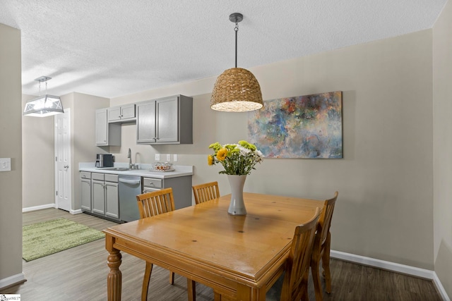 dining room featuring baseboards, a textured ceiling, and light wood-style flooring