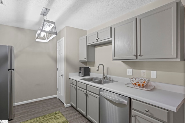 kitchen featuring gray cabinets, stainless steel appliances, light countertops, and a sink